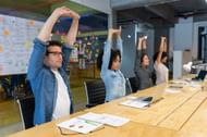 Workers doing stretching exercises at the office (Image via Getty Images)